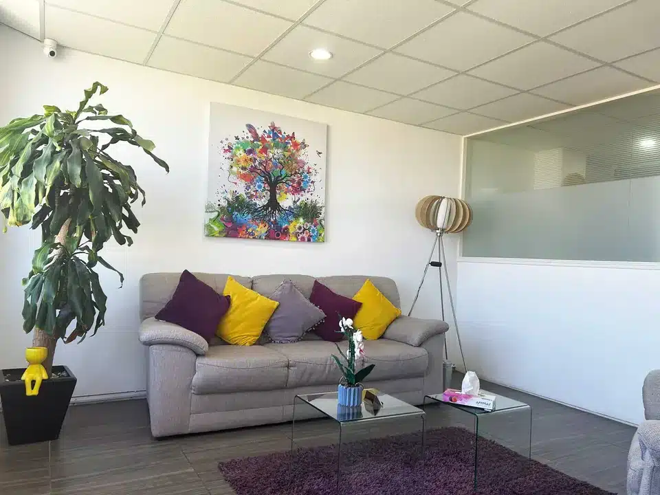 Consultorio de Psicoterapia Integral Metepec, con un sofá gris y un cuadro colorido de un árbol