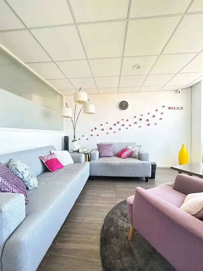 Consultorio de Psicoterapia Integral Metepec, con sofás grises y decoración floral